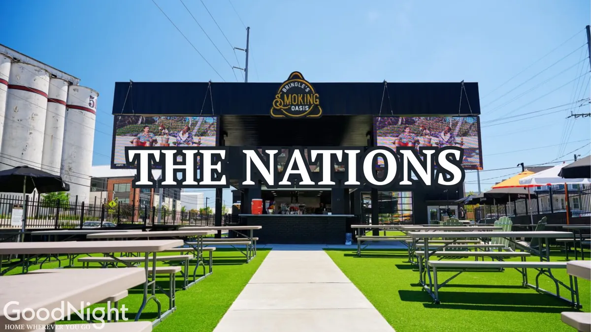 This exterior scene captures an outdoor barbecue and lounge area, featuring a prominent sign, outdoor seating, a barbecue cooking station, and digital screens displaying food and event information. The atmosphere is festive, welcoming, and perfect for social evenings.